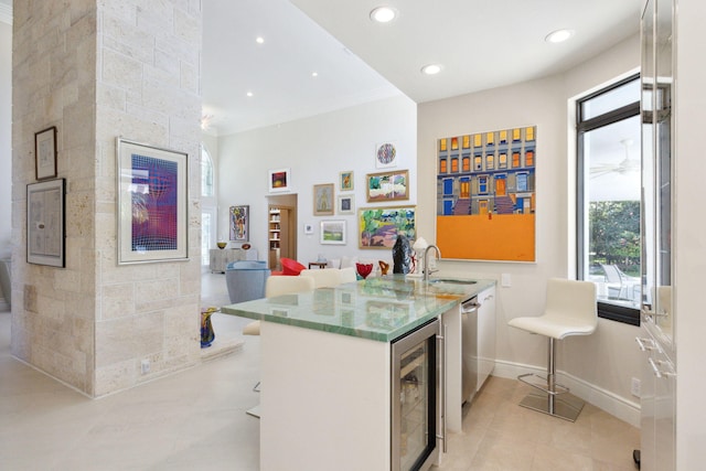 kitchen with kitchen peninsula, beverage cooler, light tile patterned floors, tile walls, and white cabinets