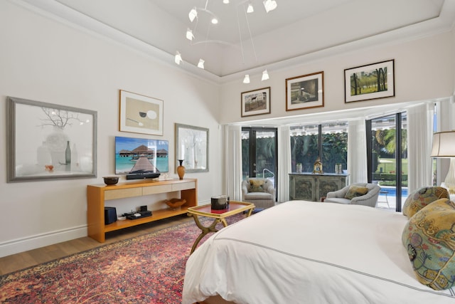 bedroom with a tray ceiling, access to exterior, ornamental molding, and hardwood / wood-style flooring