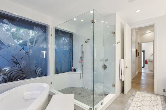 bathroom featuring shower with separate bathtub, hardwood / wood-style flooring, and ornamental molding