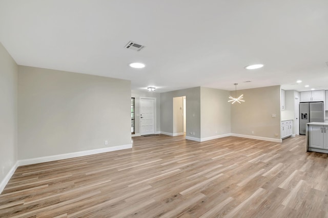 unfurnished living room featuring light hardwood / wood-style flooring and a chandelier