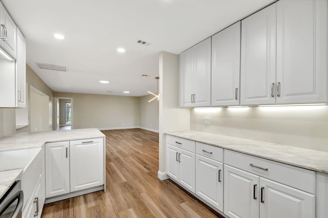 kitchen featuring white cabinetry, light stone counters, dishwashing machine, kitchen peninsula, and light hardwood / wood-style floors