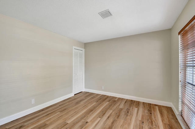 spare room featuring a textured ceiling and light wood-type flooring