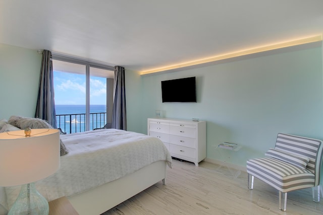 bedroom featuring access to outside, expansive windows, and light hardwood / wood-style floors