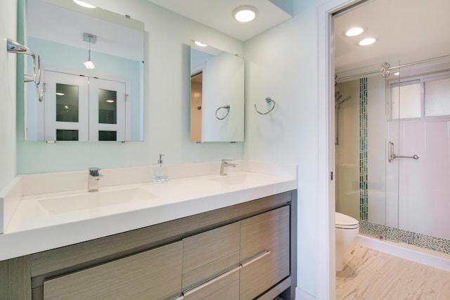 bathroom with walk in shower, vanity, and toilet