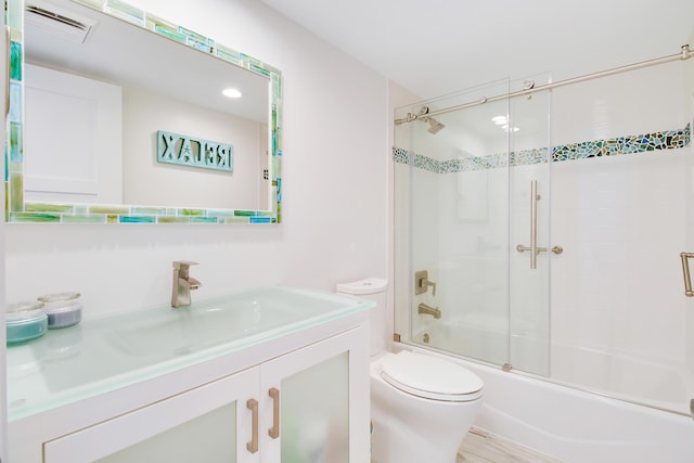 full bathroom featuring vanity, toilet, and bath / shower combo with glass door