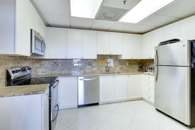 kitchen featuring sink, light tile patterned floors, appliances with stainless steel finishes, light stone counters, and white cabinetry