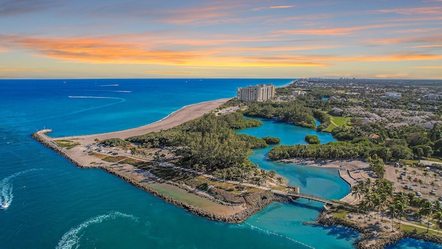 aerial view at dusk featuring a water view and a view of the beach