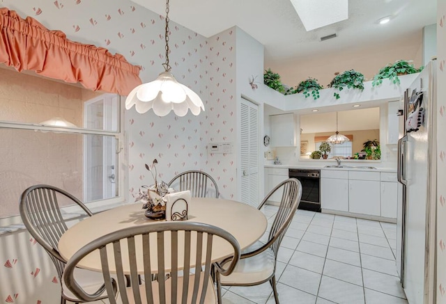 dining room featuring light tile patterned flooring, sink, and a skylight