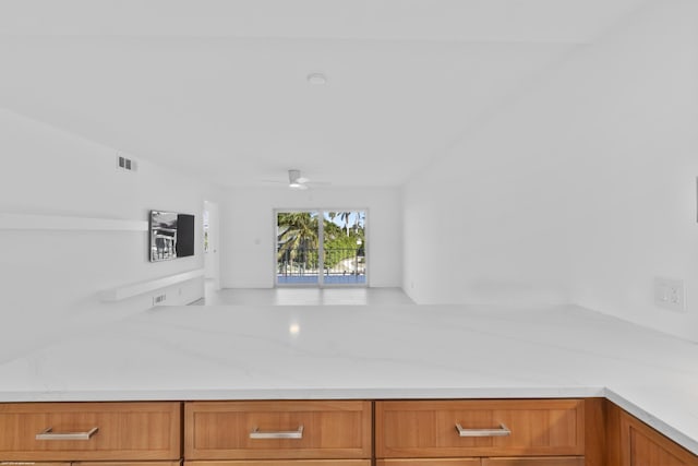 kitchen featuring ceiling fan and light stone countertops