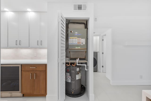 utility room featuring wine cooler, electric water heater, heating unit, and washer / clothes dryer