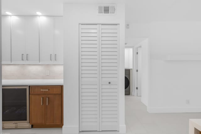 kitchen featuring backsplash, washer / clothes dryer, white cabinets, and beverage cooler