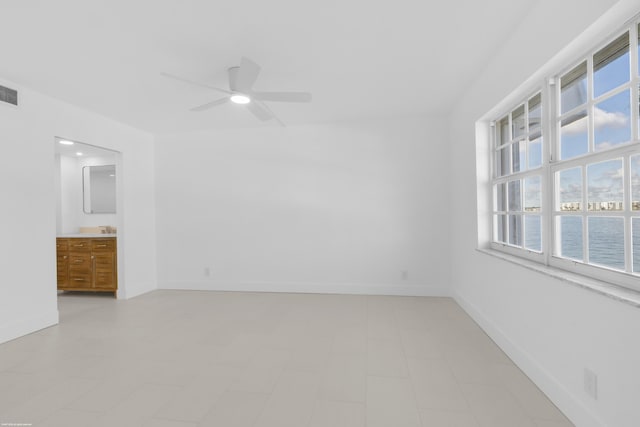 spare room featuring a water view, plenty of natural light, and ceiling fan