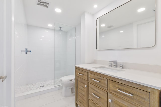 bathroom with a tile shower, tile patterned flooring, vanity, and toilet