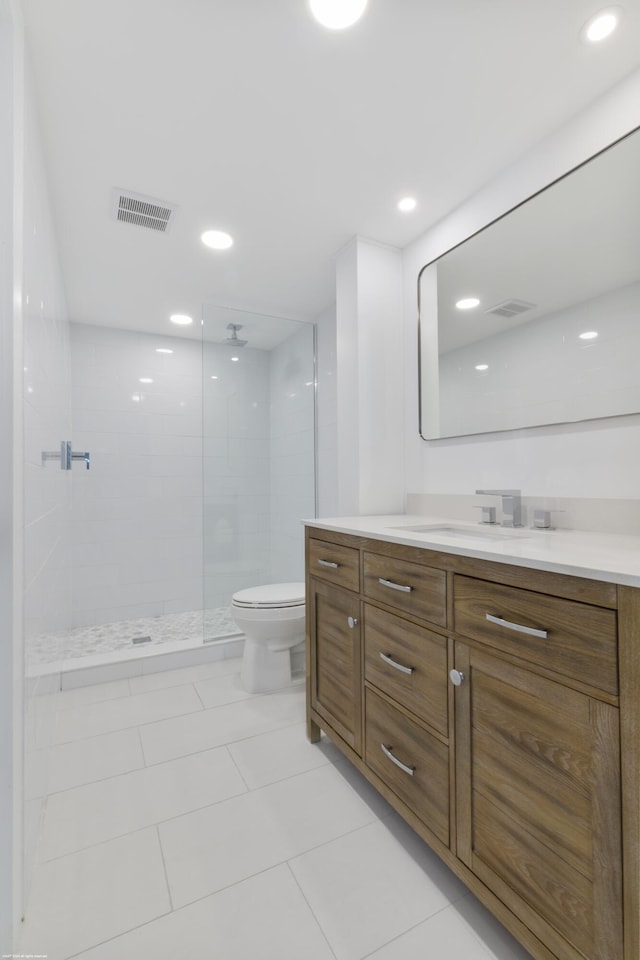 bathroom with tile patterned flooring, a tile shower, vanity, and toilet