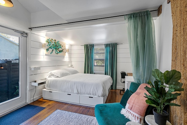 bedroom with multiple windows, hardwood / wood-style floors, and vaulted ceiling