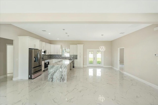 kitchen with pendant lighting, a center island, white cabinets, light stone countertops, and stainless steel appliances