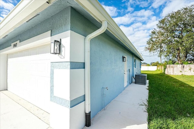 view of side of home featuring cooling unit, a garage, and a yard