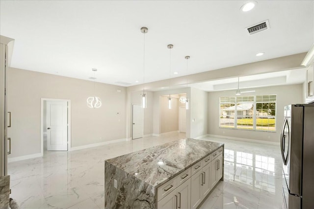 kitchen featuring stainless steel fridge, a center island, pendant lighting, and light stone counters