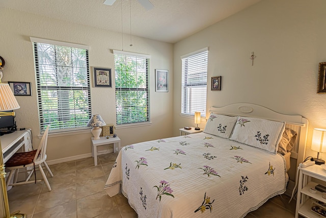 tiled bedroom with ceiling fan, multiple windows, and a textured ceiling