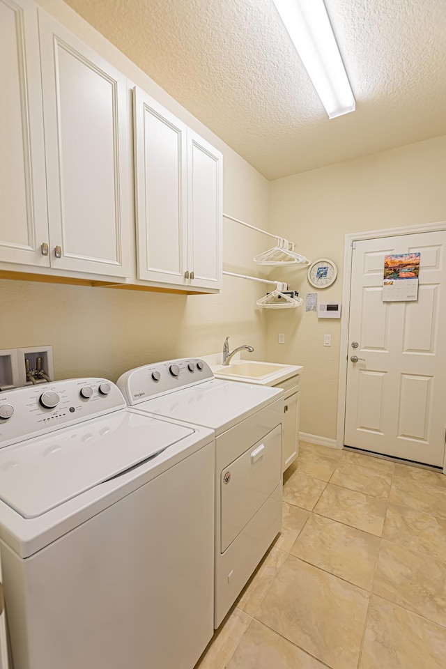 laundry area featuring sink, cabinets, light tile patterned floors, washing machine and dryer, and a textured ceiling