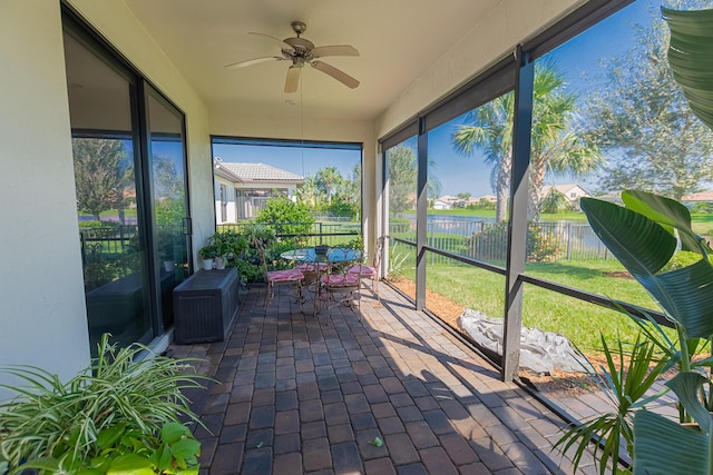 unfurnished sunroom with a water view and ceiling fan