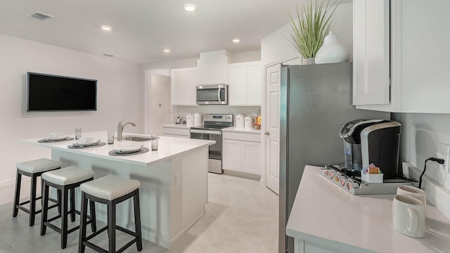 4601 SW Savona Blvd, Port Saint Lucie, FL 34953 - kitchen featuring visible vents, white cabinets, a sink, appliances with stainless steel finishes, and a breakfast bar