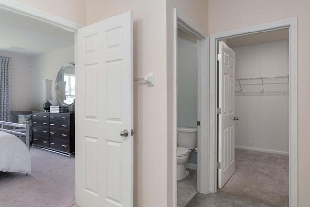 bedroom featuring light colored carpet, a walk in closet, and a closet