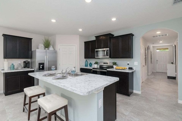 kitchen featuring a kitchen breakfast bar, sink, stainless steel appliances, and an island with sink