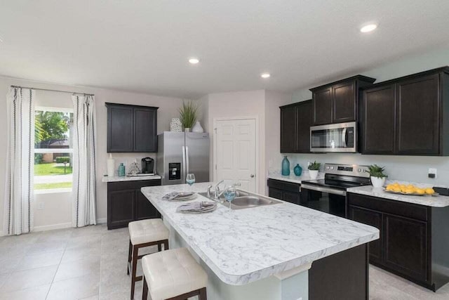 kitchen featuring sink, a kitchen bar, stainless steel appliances, and a kitchen island with sink