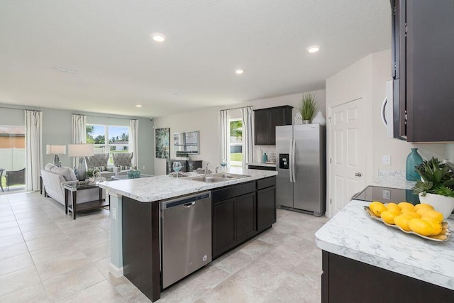 kitchen with sink, an island with sink, light tile patterned floors, and appliances with stainless steel finishes