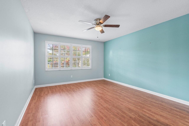 empty room with ceiling fan, wood-type flooring, and a textured ceiling