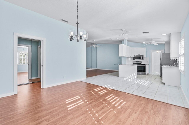 kitchen with light hardwood / wood-style floors, white cabinetry, hanging light fixtures, and appliances with stainless steel finishes