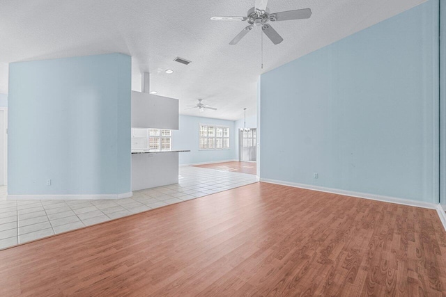 unfurnished living room featuring ceiling fan, light hardwood / wood-style flooring, and a textured ceiling