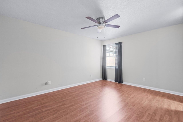 empty room with ceiling fan, wood-type flooring, and a textured ceiling