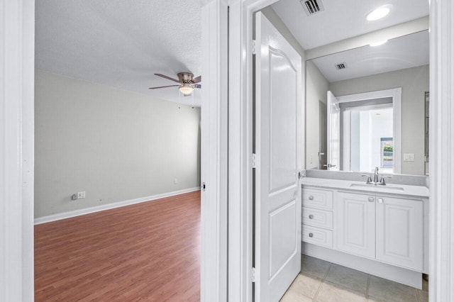 bathroom featuring a textured ceiling, vanity, hardwood / wood-style flooring, and ceiling fan