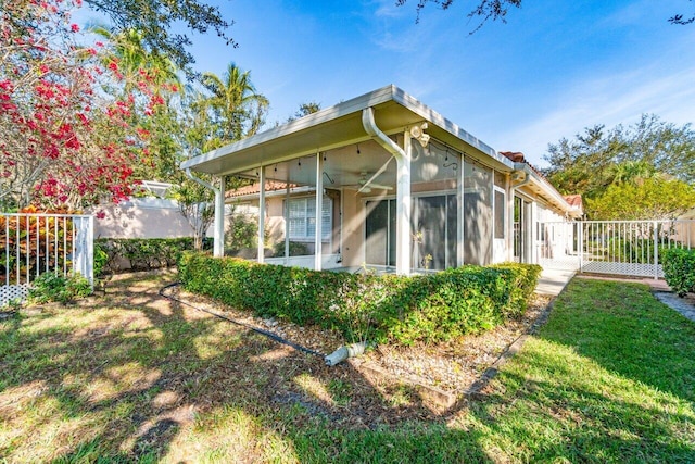 rear view of house featuring a lawn and a sunroom