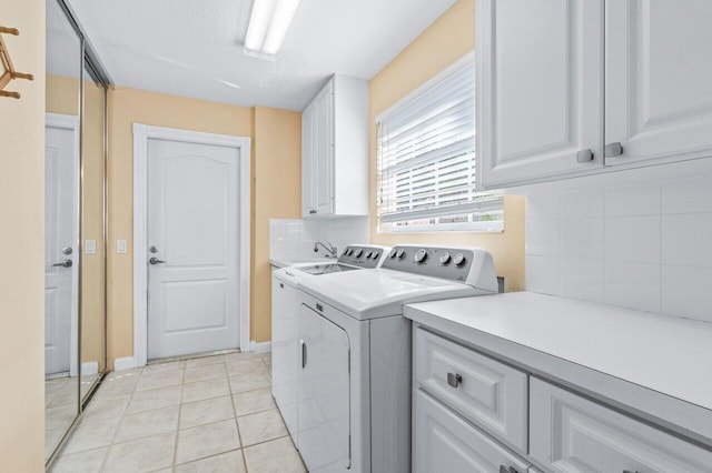 clothes washing area with cabinets, light tile patterned floors, and washing machine and clothes dryer