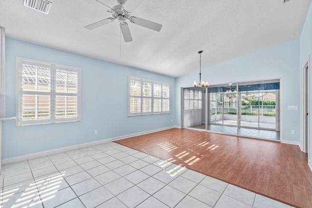 unfurnished room with ceiling fan with notable chandelier, light wood-type flooring, a textured ceiling, and vaulted ceiling