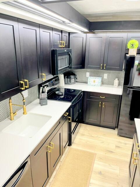 kitchen featuring decorative backsplash, sink, appliances with stainless steel finishes, and light hardwood / wood-style flooring