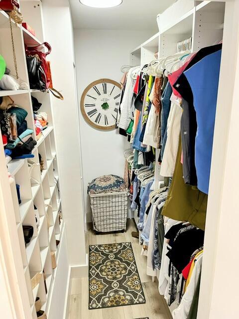 walk in closet with light hardwood / wood-style flooring