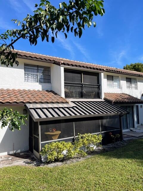 rear view of house featuring a lawn and a balcony