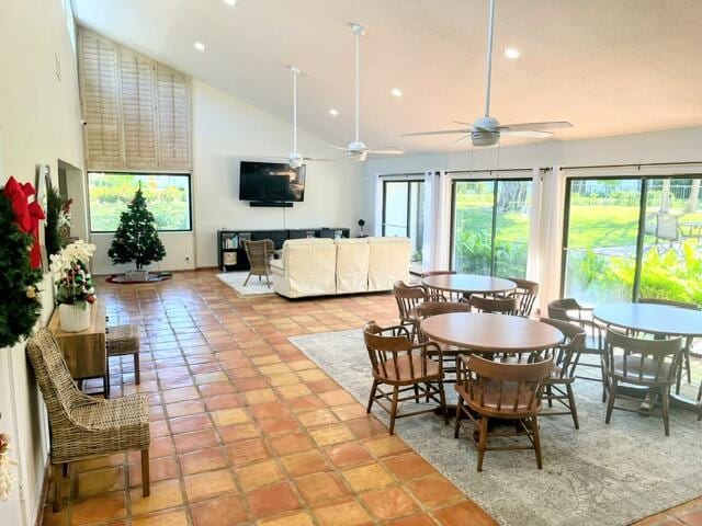 dining space with ceiling fan, high vaulted ceiling, and light tile patterned flooring