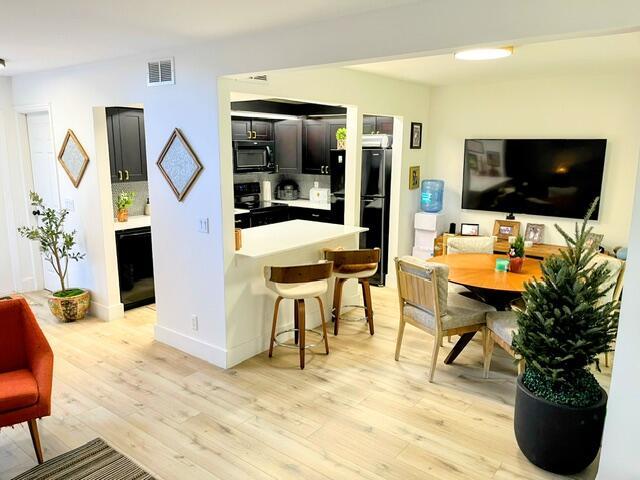 kitchen featuring a breakfast bar area, black appliances, and light wood-type flooring