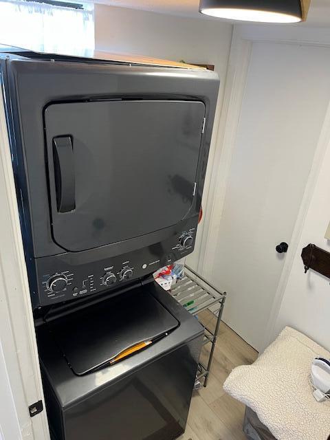 laundry room featuring light wood-type flooring and stacked washer and dryer