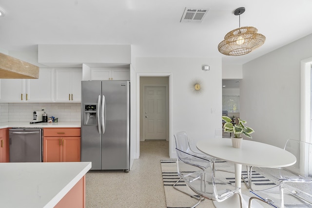 kitchen with decorative backsplash, white cabinets, decorative light fixtures, and appliances with stainless steel finishes