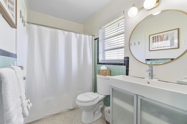 bathroom with a shower with curtain, vanity, toilet, and tile walls