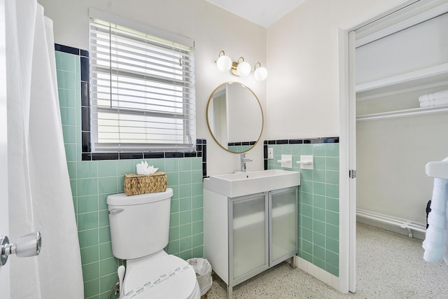 bathroom with vanity, toilet, and tile walls