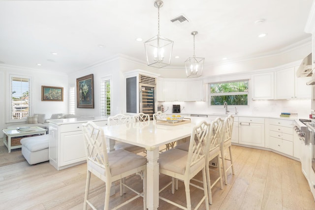 kitchen featuring pendant lighting, a center island, a kitchen breakfast bar, light hardwood / wood-style flooring, and white cabinetry