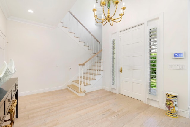 foyer with an inviting chandelier, ornamental molding, and light wood-type flooring