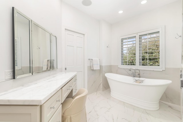 bathroom with vanity, tile walls, and a tub